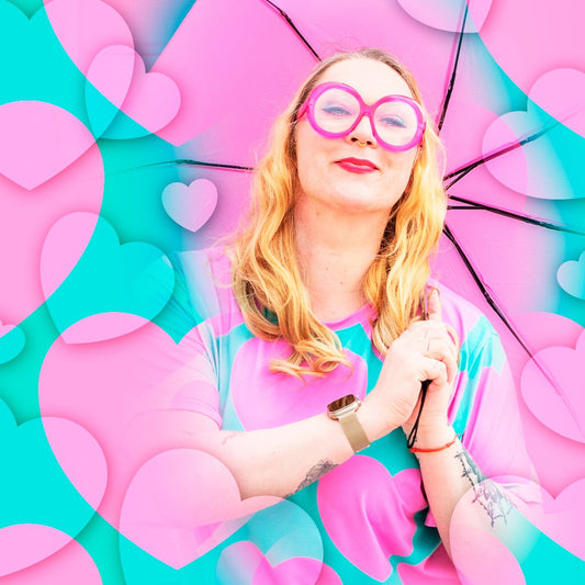 A smiling woman in pink glasses surrounded by pink hearts, wearing ELLIE LOVE pink mint t-shirt dress by SHALMIAK.