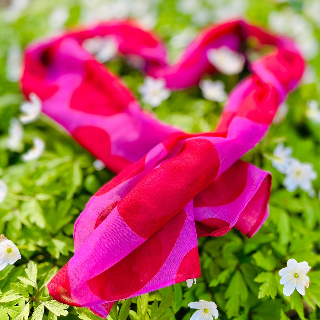 Colorful heart design scarf arranged in a heart shape among spring flowers.