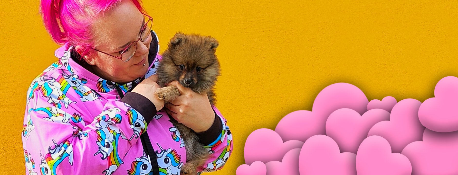 Woman in a colorful SHALMIAK hoodie with unicorns. Picture includes a cute puppy dog and a lot of pink hearts.