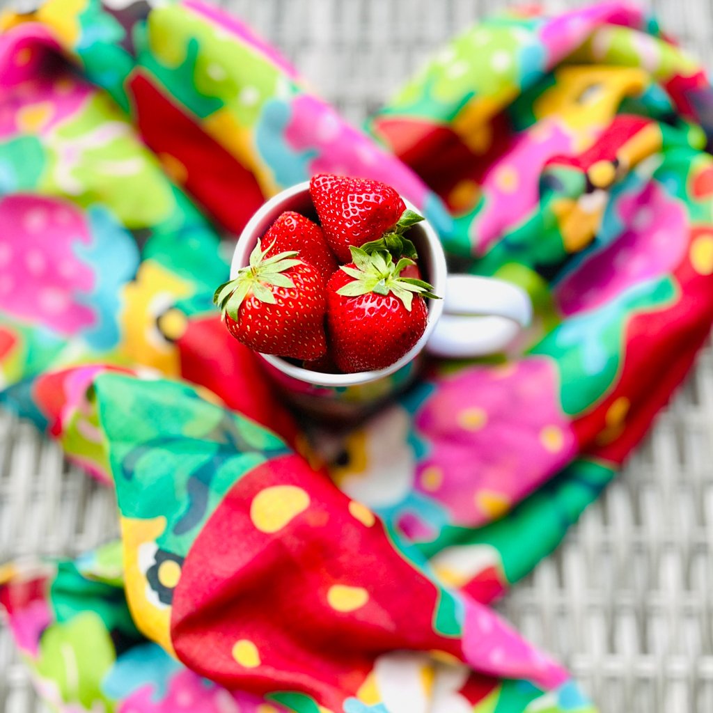 Colorful heart-shaped scarf with fresh strawberries inColorful scarf styled in a heart shape with fresh strawberries in a mug.