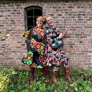 Two women in colorful midi dresses by SHALMIAK. Designs: FLORA FOREVER retro and MAGICAT black.